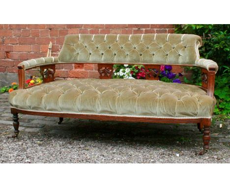 A late 19th century mahogany and upholstered salon sofa, carved support slats, curved form, turned knop and baluster legs on 