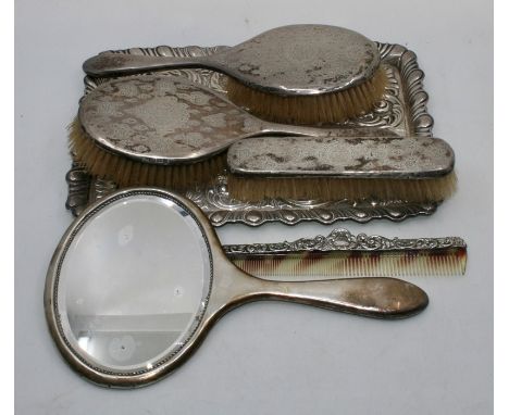 An early 20th century silver dressing set:- comprising a mirror unmarked, two large brushes Birmingham 1934 and 1936, a small