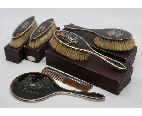 
A George V silver and tortoise shell dressing set comprising:- a mirror, a comb, two large brushes in their cardboard boxes 