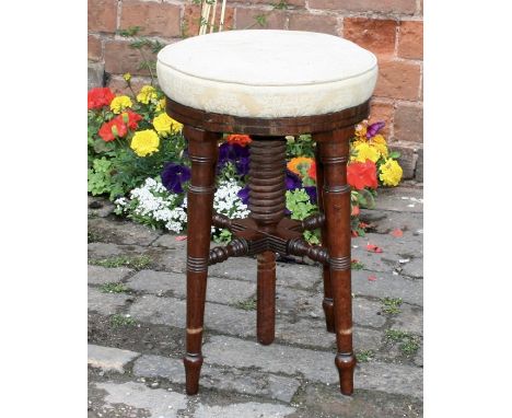 An Edwardian mahogany piano stool with circular upholstered revolving adjustable seat raised on ring turned supports and bobb