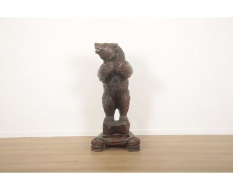 A BLACK FOREST CARVED BEAR STICK OR UMBRELLA STAND late 19th/early 20th century, with glass eyes and paws clasped, 96cm highP