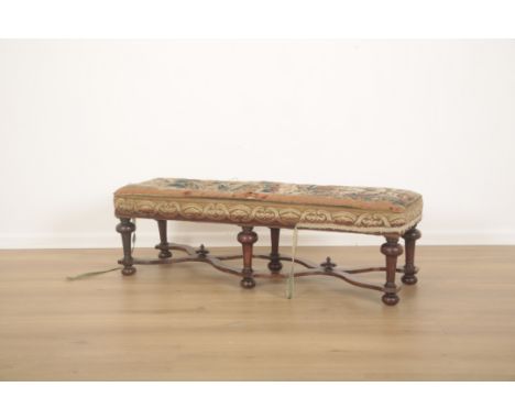 A LONG LOW STOOL IN WILLIAM AND MARY STYLE20th century, the rectangular seat upholstered in floral tapestry, with walnut doub