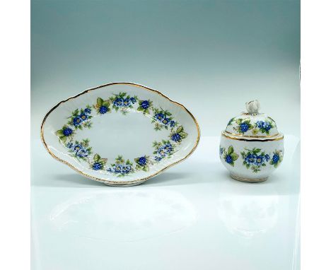 A set of two ceramic items, a sugar jar and serving tray that are primarily white with blue flowers and green shrubbery decor