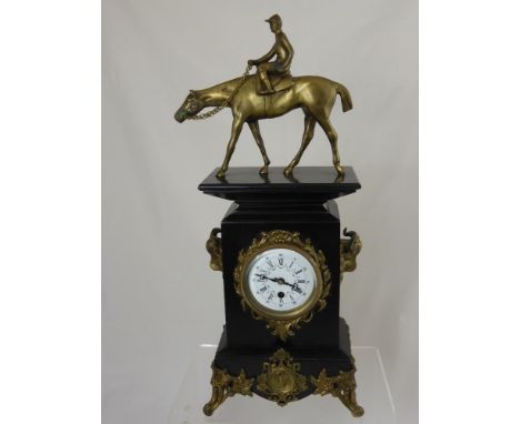 A Victorian style slate mantle clock on scroll feet with a brass figure of a jockey on horseback to the top.