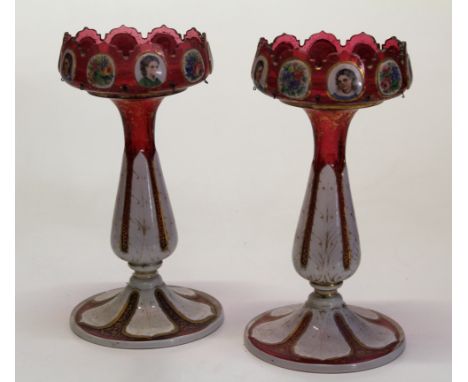 A pair of 19th century Bohemian cranberry glass and enamel table lustres, each with castellated top decorated with reserved p