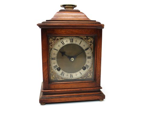 A Georgian style mahogany cased bracket clock, having a folding brass handle on the domed top, over a glazed window, on brass