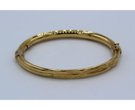 An hinged hollow bangle, stamped "750" with Italian goldsmiths marks. In as found condition due to extensive damage. Testing 