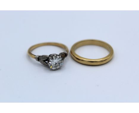 A vintage 1ct round brilliant cut diamond solitaire ring, together with a yellow metal band ring. The solitaire is set in a c