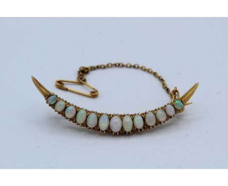 A Victorian style opal set celestial crescent brooch. Set with 13 graduated opal cabochonsTesting as 14ct gold. With c clasp 