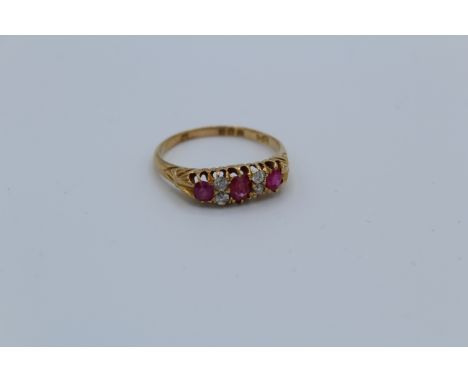 An Edwardian 18ct gold diamond and ruby set half hoop ring. Set with three oval mixed cut rubies, interspersed with four old 