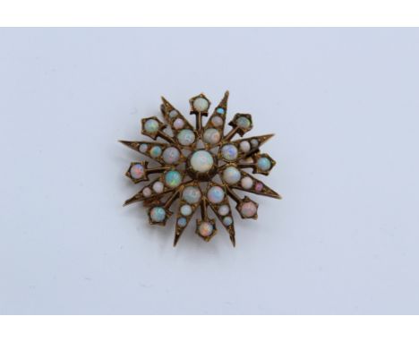 A 9ct gold Victorian style starburst brooch, set with opal. Set with 33 round vari-size opal cabochons.  With rollover bolt c