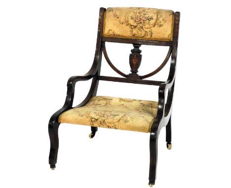 An Edwardian mahogany and marquetry inlaid nursing chair, with a padded back and seat, raised on sabre legs with ceramic cast