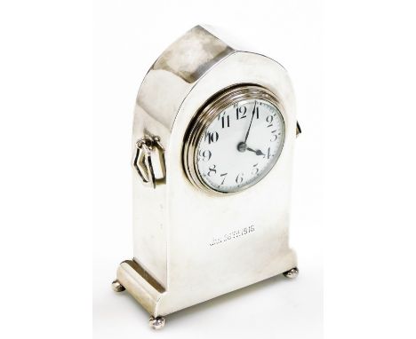 An early 20thC silver cased mantel clock, in a plain lancet shaped case, with two ring handles, the white enamelled dial bear