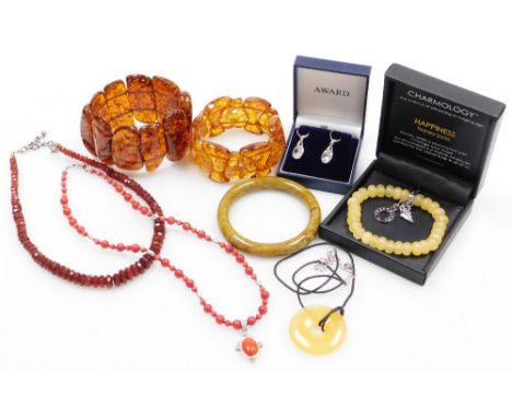 A group of assorted costume jewellery, comprising imitation amber bracelets, coral necklace, carved soapstone bangle, Happine