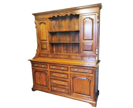 A Georgian style oak and mahogany cross banded dresser, the outswept pediment and dental moulding, above a carved frieze and 