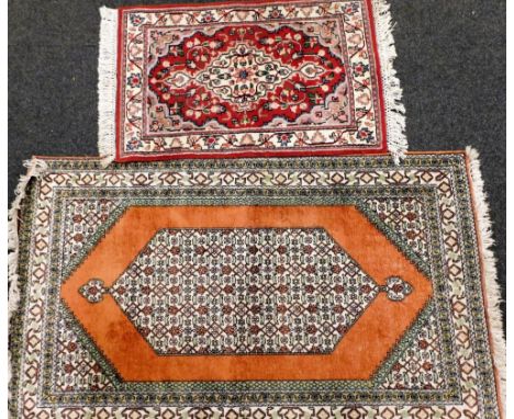 A Persian type rug, decorated with a pearl medallion, on an orange ground with multiple borders and spandrels, (AF), and a sm