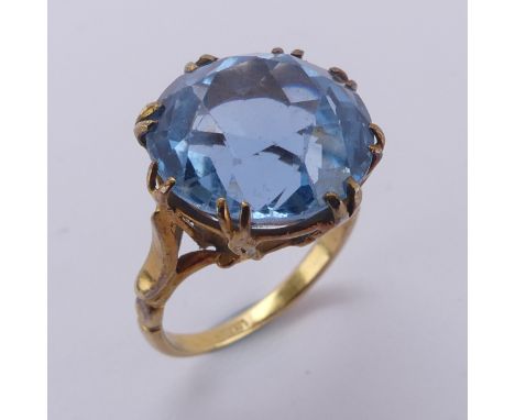 A circular facetted blue stone Ring, approx. 14mm diameter, claw set in an 18ct yellow gold cagework mount, Size K, 6.8g, pro