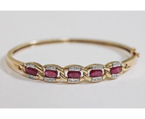 A diamond chip and ruby bangle, marked '375 DIA', diam. 5.5cm, gross wt. 12.3g.