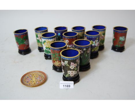 Set of twelve Chinese small cloisonne floral decorated beakers on hardwood stands, with blue enamel interior and a small cloi