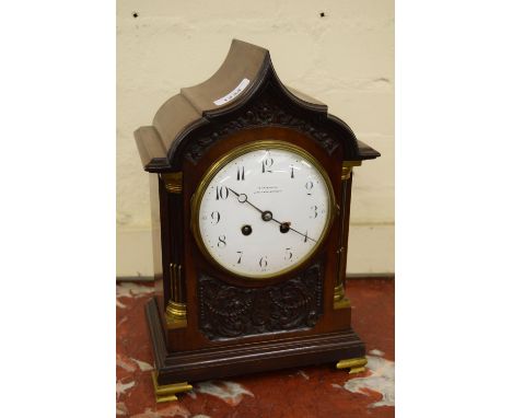 Edwardian mahogany mantel clock, the shaped arch top case with flanking quarter pilasters and carved decoration with brass mo