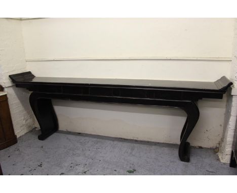 Large Chinese black lacquer altar table, the narrow top with scroll ends, raised on scroll shaped supports with carved decora