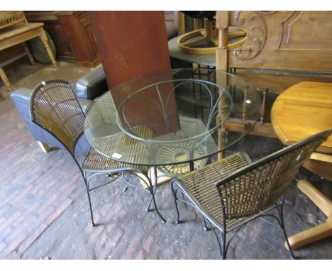 Circular glass garden table with painted wrought iron base together with four matching chairs with caned back and seats, the 