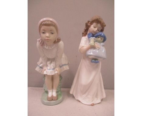 Two Nao figures to include one of a girl holding a doll 
