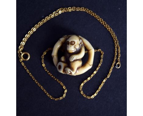 A Japanese netsuke from the Meiji period in the form of a monkey seated in a window, with gilt metal chain