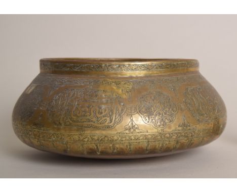 An Islamic brass bowl engraved with calligraphy and foliage