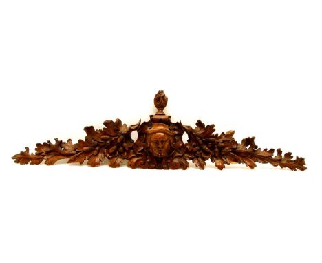 A Continental carved oak bracket, late 19th century, with a flaming finial and man's head flanked by acorns and oak leaves, 1