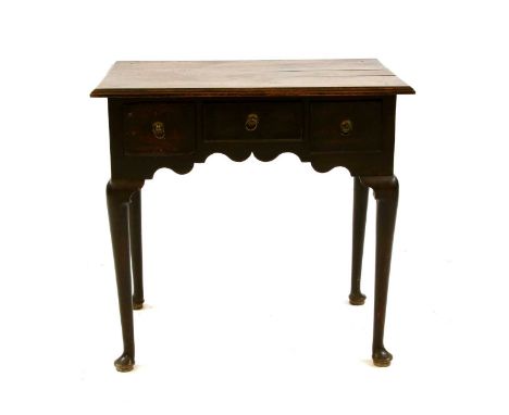 An 18th century oak lowboy, with three drawers, brass penny &amp; ring handles and rule moulded plank top, on column legs and