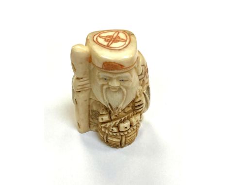 A Japanese carved bone netsuke - Village elder with a basket at his feet. 