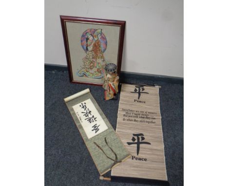 A needlework panel depicting a geisha, framed, together with a 20th century geisha doll, Japanese scroll and wall hanging 