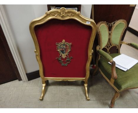 A VICTORIAN GILTWOOD AND GESSO FRAMED FIRESCREEN, of shaped rectangular outline, with crimson fabric panel applied with embro