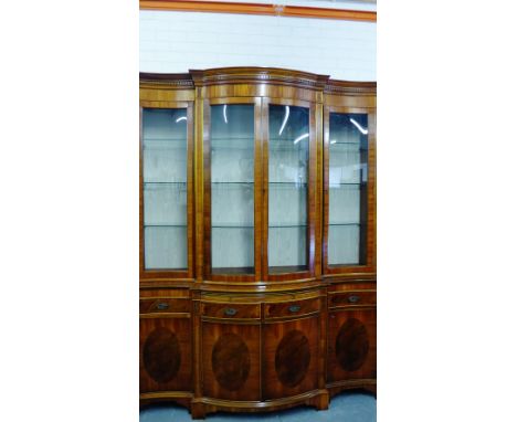 A mahogany breakfront bookcase cabinet with a dentil frieze over a pair of bow front central glazed doors flanked by another,