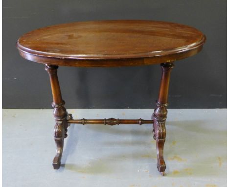 A Victorian mahogany side table, the oval top with moulded edge on twin turned and carved supports and stretcher, terminating