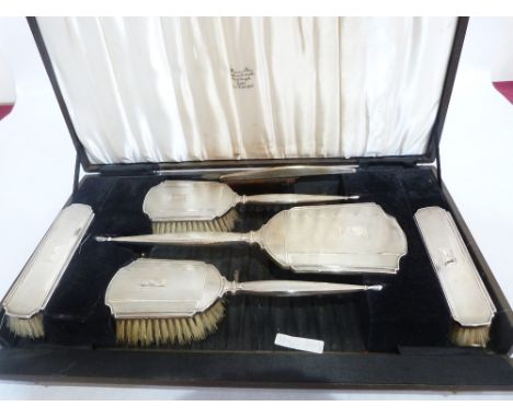 A George VI cased silver six piece dressing table set, comprising hand mirror, two hair brushes, two clothes brushes and a co