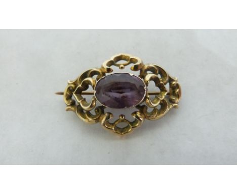 A Victorian yellow metal openwork brooch set with an amethyst