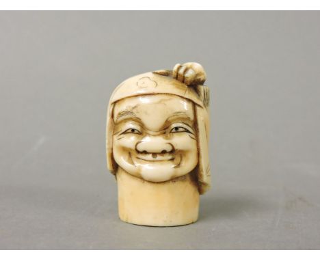 An ivory walking stick pommel, circa 1880, carved as a man smiling as a crab crawls over his headdress, 4.2cm