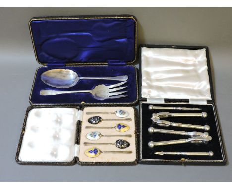 A cased set of silver and enamel teaspoons, silver plated serving spoon and fork, and nutcrackers