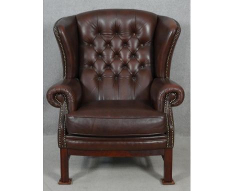 A Georgian style wing back armchair by Christie Tyler in deep buttoned leather studded upholstery on mahogany square section 