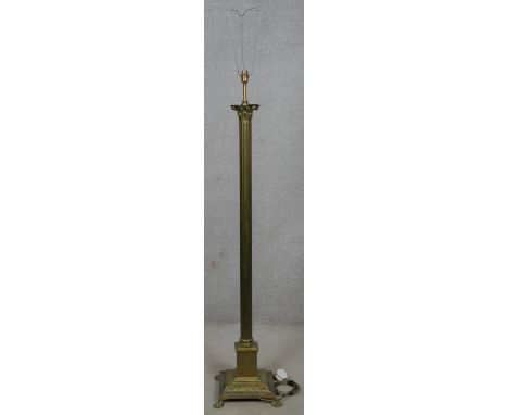 A vintage brass standard lamp in the form of a Corinthian column standing on a stepped base resting on lion's paw feet. H.163