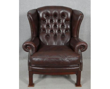 A Georgian style wing back armchair by Christie Tyler in deep buttoned leather studded upholstery on mahogany square section 