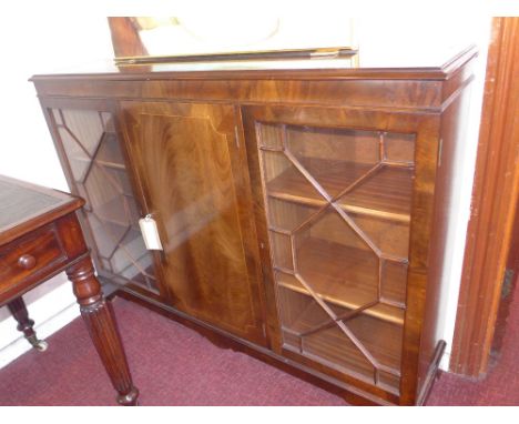 A mahogany bookcase, having a central door flanked by astragal glazed doors raised on shaped bracket supports  