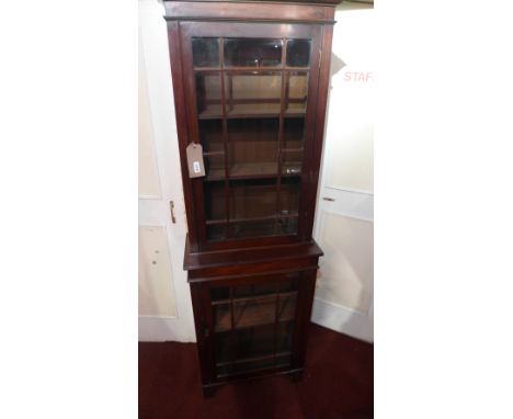 A Victorian mahogany bookcase of slender form with one glazed door over another, raised on shaped bracket supports 