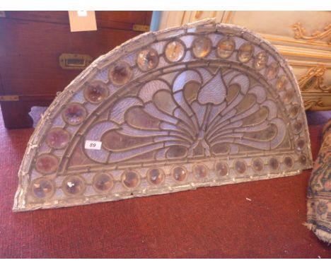 An early 20th century leaded stained glass panel of demi lune form 