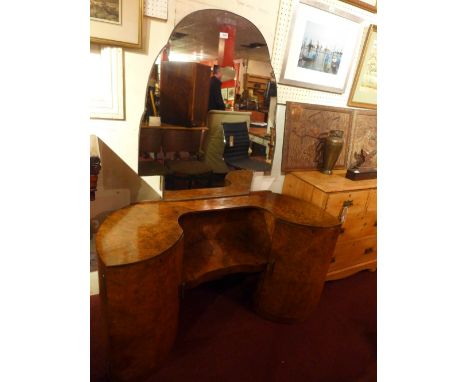 An Art Deco figured walnut dressing chest the shaped frameless mirror over a shelf flanked by cupboard doors 