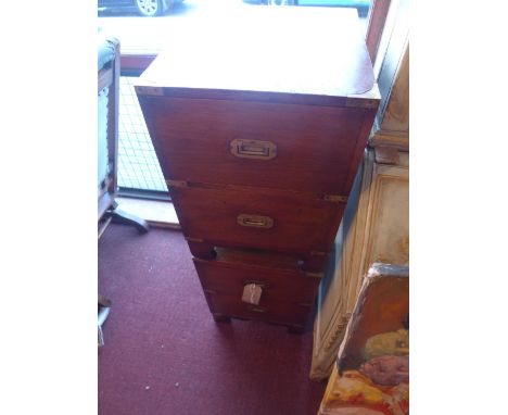 A pair of campaign style mahogany and brass bound bedside chests of two drawers raised on shaped bracket supports 