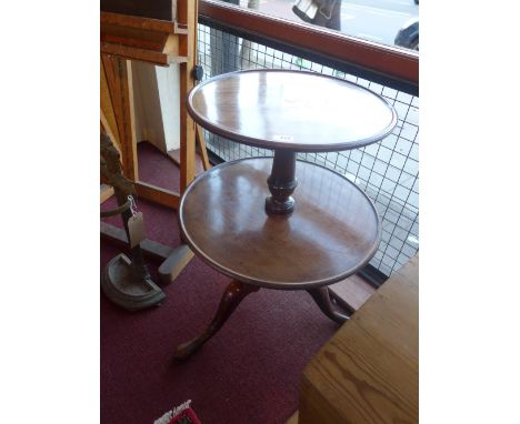 A George III mahogany two tier dumb waiter with a turned stem, raised on tripod supports 