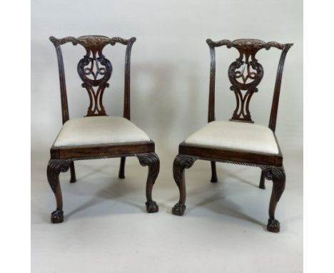 A pair of George III carved mahogany side chairs, each with a shaped top rail and pierced splat and drop in seat, on acanthus